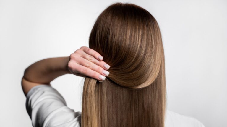 mulher de costas segurando o cabelo de mega hair